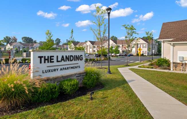 the landing apartments sign in front of street with houses
