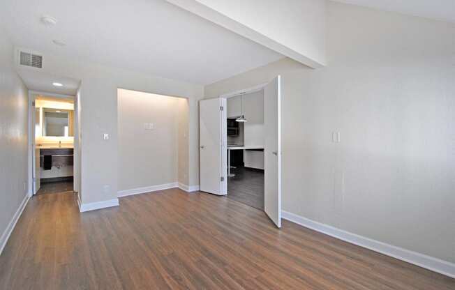 a spacious living room with wood flooring and a door to a kitchen