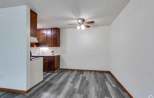 an empty living room and kitchen with a ceiling fan