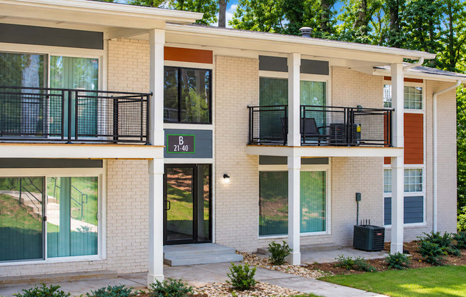 Building B exterior with white brick, black balcony railings and a central entrance at Icon Avondale Apartments in Decatur, GA.