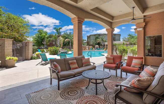 A patio with a couch, chairs, and a table with a rug.