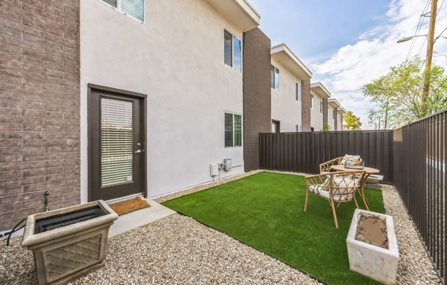 a yard with a table and chairs in front of a building