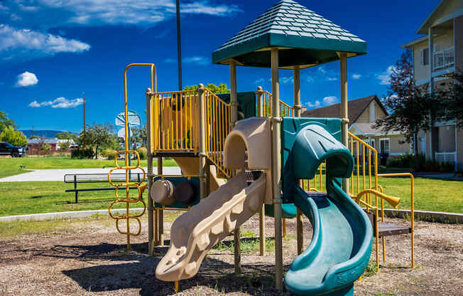 A playground with a green slide and a yellow structure.