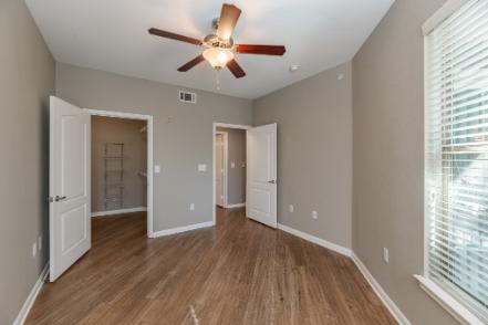 A room with a ceiling fan and wooden floors.