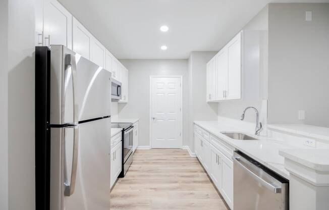 a white kitchen with stainless steel appliances and white cabinets