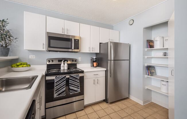 A kitchen with a stove, refrigerator, and microwave.