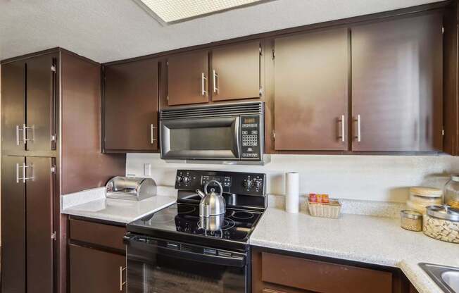 A kitchen with brown cabinets and a black stove top oven.
