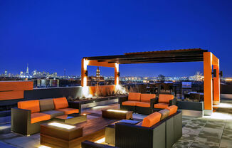 a terrace with couches and a fire pit overlooking a city at night