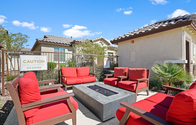 a patio with red chairs and a fire pit