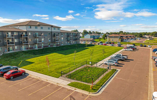 A parking lot with cars and a grassy area in front of a building.