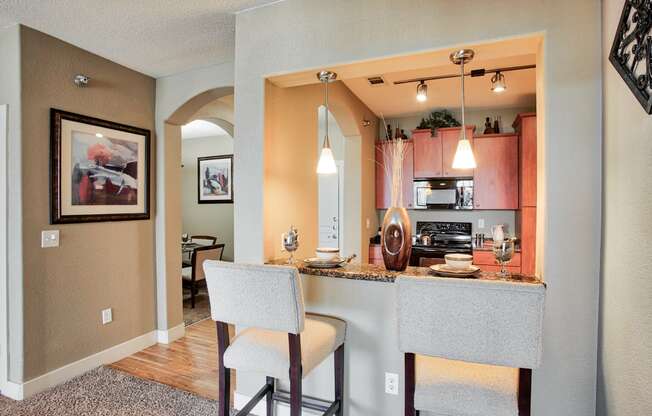 a kitchen with a breakfast bar and a dining room in the background At Metropolitan Apartments in Little Rock, AR