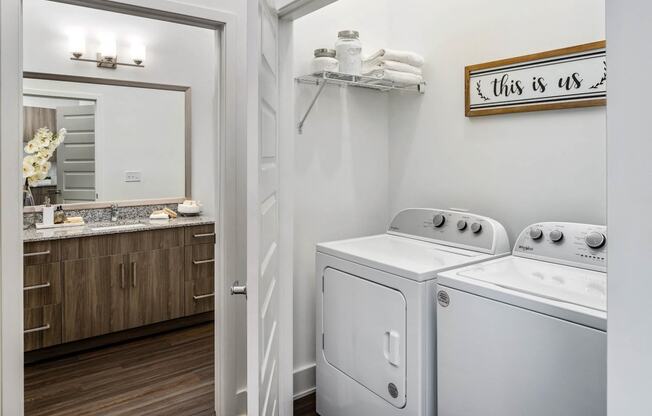 a white washer and dryer in a room with a mirror and a bathroom