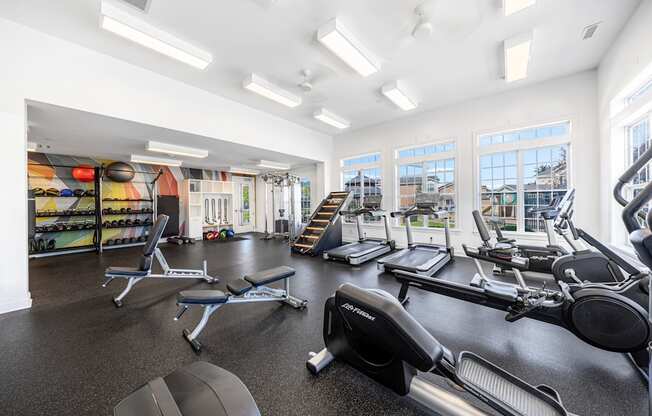 A gym with a variety of equipment including treadmills, weights, and exercise machines.