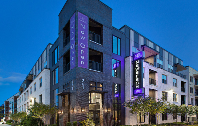 The exterior of the Newbergh ATL apartment complex in Atlanta, featuring a view of the light up sign.