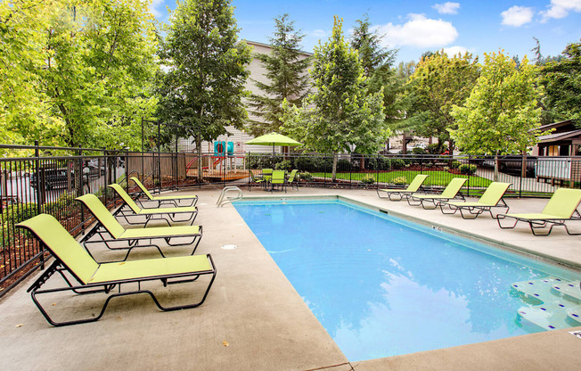 a swimming pool with chaise lounge chairs and trees