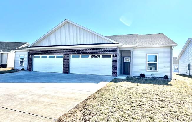 A two-car garage is attached to a white house.