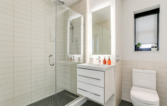 Bright tiled bathrooms with large backlit designer mirror, Hans Grohe chrome fixtures and Villeroy & Boch vanity