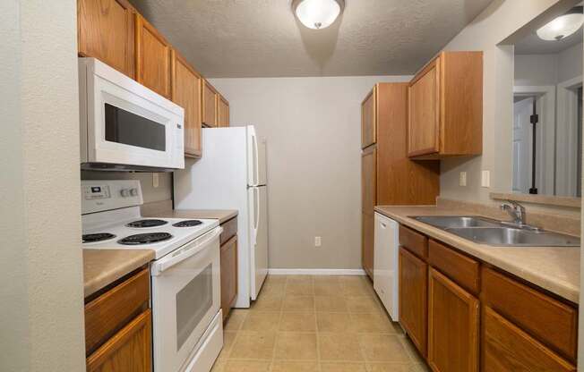 A kitchen with white appliances and wooden cabinets.