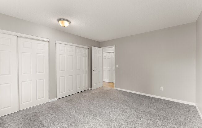 A room with three white doors and a grey carpet.