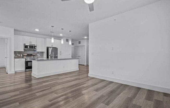 an empty living room and kitchen with white walls and wood floors