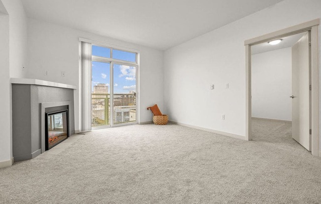 A large, empty room with a fireplace and a window overlooking a cityscape.