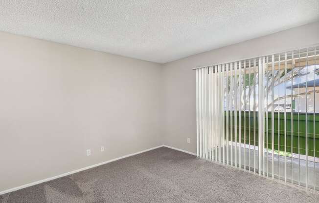 an empty living room with a large window and white blinds