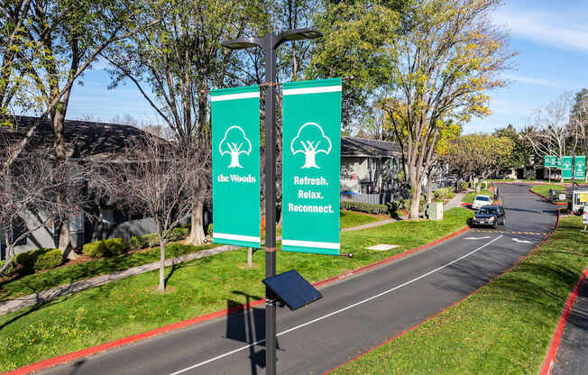 Two green signs with trees and the words "The Woods" and "Refresh" on them.