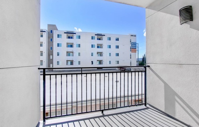 a balcony with a black railing and a white building in the background