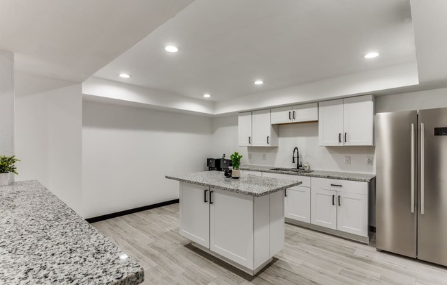 a kitchen with white cabinets and granite counter tops and a stainless steel refrigerator