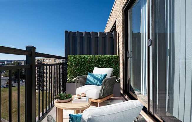 A balcony with a table, chairs, and a potted plant.