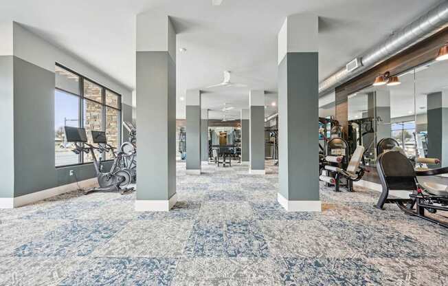 a gym with exercise machines and a blue and white carpet in a building at The Quarry Luxury Apartment Homes, Fort Collins, CO, 80526
