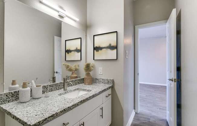 A bathroom with a granite countertop and two sinks.