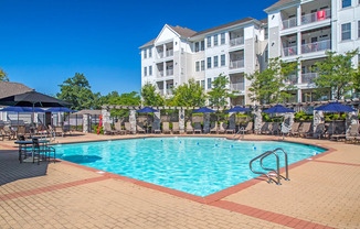 a swimming pool at an apartment complex with umbrellas
