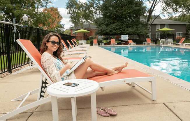 a woman sits in a chair next to a pool with a laptop on her lap at The View Apartments St Charles, St Charles, 60174