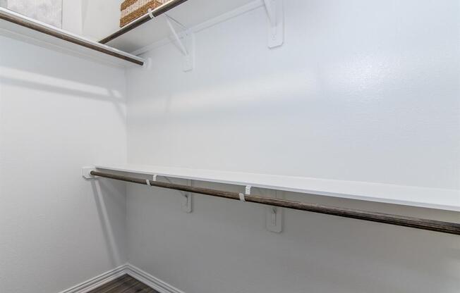 a walk in closet with white walls and a white shelf