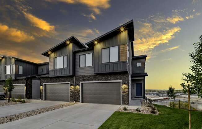 a house with two garage doors and a sunset in the background