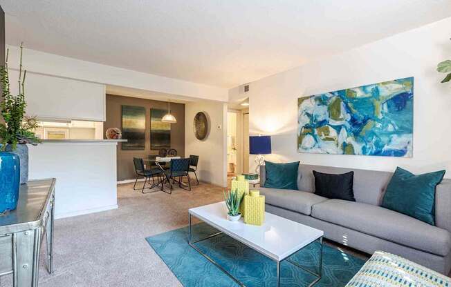 A living room with a grey couch, a white coffee table, and a blue rug.