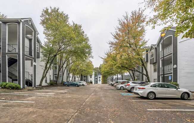 A parking lot with cars and apartment buildings on either side.