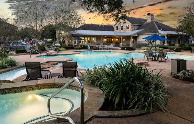 A pool area with a hot tub and chairs in front of a house.