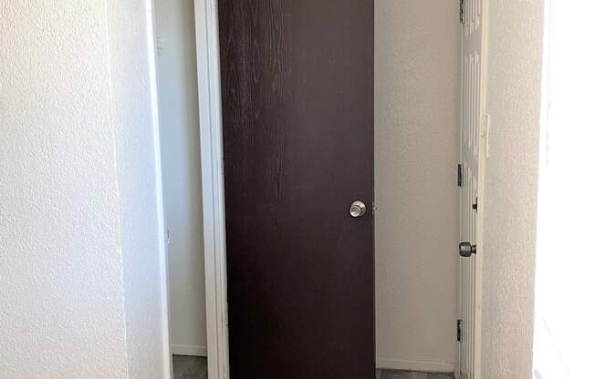 A brown door is in a white hallway.