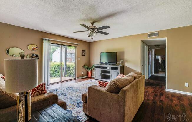 a living room with couches and a tv and a ceiling fan