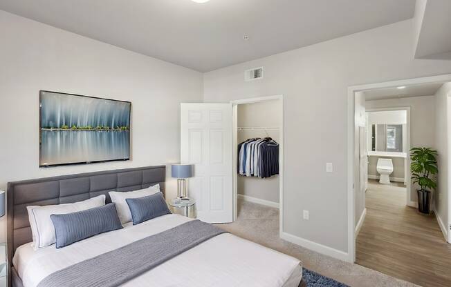 A bedroom with a large bed and a painting on the wall.