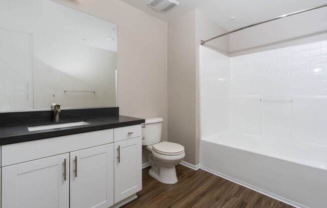 A white bathroom with a toilet, sink, and a shower.