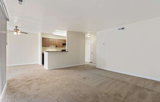 an empty living room and kitchen with a ceiling fan