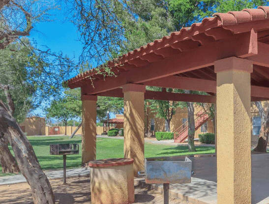 Outdoor covered picnic area with charcoal grilling station overlooking property landscaping