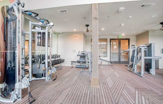 a gym with weights and cardio machines and a glass door  at Edge and Stone, San Antonio