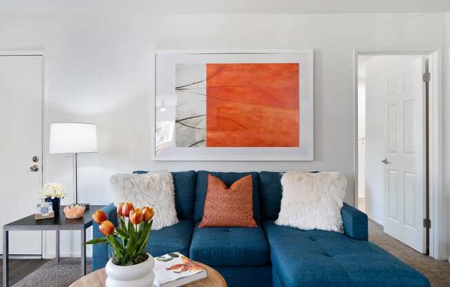 a living room with a blue couch and orange artwork