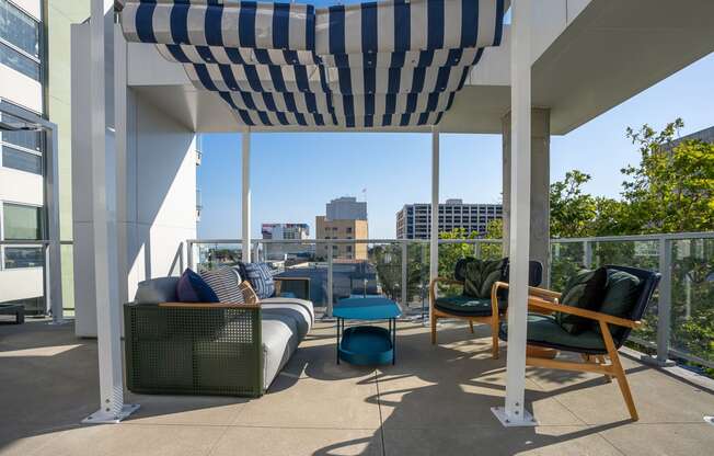 a pergola on a balcony with furniture and a view of the city