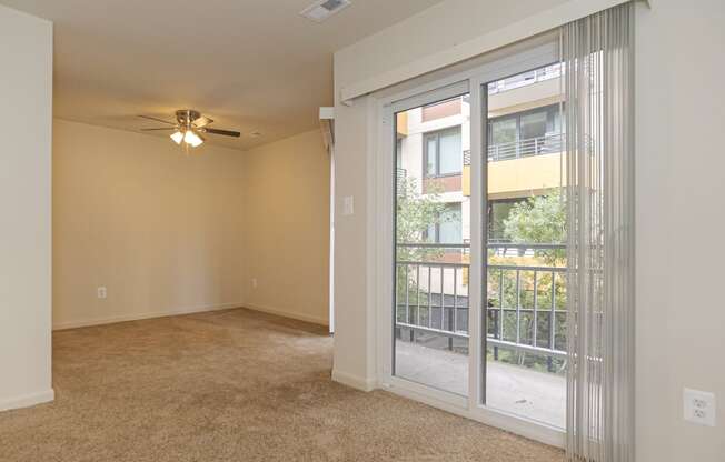 an empty living room with a large window and a ceiling fan