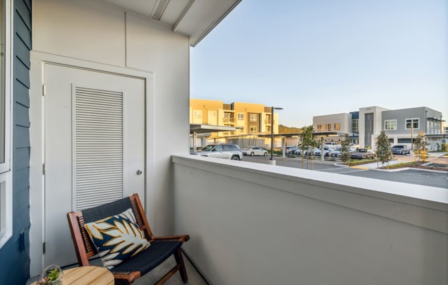 a balcony with a chair and a window overlooking a street